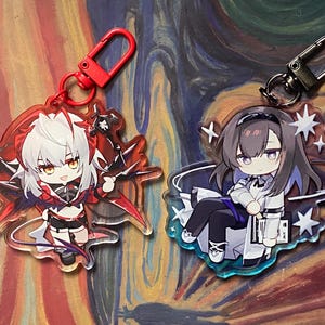 May include: Two anime-style acrylic keychains. One features a character with white hair and red accents, the other a character with dark hair and a white and black outfit. Both have metal clasps for attaching to keys or bags.