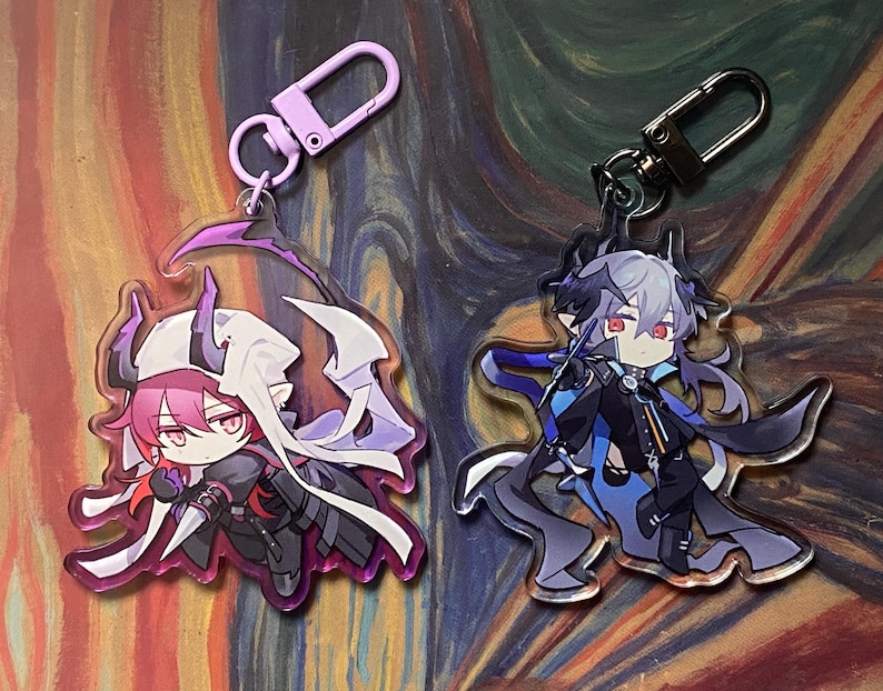 May include: Two acrylic keychains featuring anime-style characters. One keychain has a pink-haired character with a white cape and purple accents. The other has a gray-haired character with blue and black accents. Both have metal clasps.