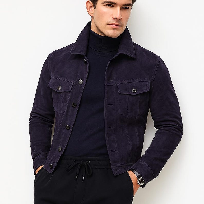Puede incluir: Chaqueta de ante azul marino con dos bolsillos en el pecho y cierre de botones. La chaqueta tiene un cuello cl&aacute;sico y se lleva sobre un cuello alto azul marino. El modelo lleva pantalones negros y un reloj.