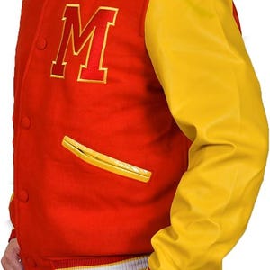 May include: Red and yellow varsity jacket with a large letter "M" on the chest. The jacket has a red body, yellow sleeves, and a white and red striped collar and cuffs. Features two yellow trimmed pockets.