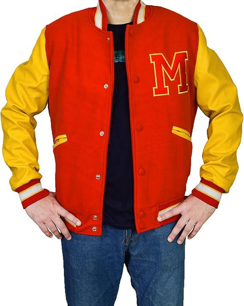 May include: A red and yellow varsity jacket with the letter "M" on the chest. The jacket has yellow sleeves, a red body, and white and red striped cuffs. It features a button-up front and two front pockets.