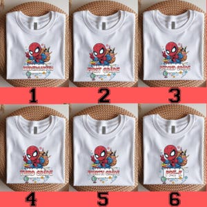 May include: A collection of six white t-shirts, each featuring a graphic of a cartoon superhero wearing a backpack and making a peace sign. Below the character, text indicates different school levels: Kindergarten, First Grade, Second Grade, Third Grade, Fourth Grade, and Pre-K, accompanied by small illustrations of a globe, pencils, and books.