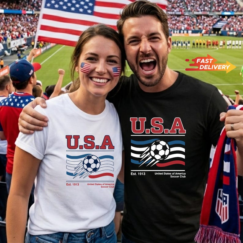 May include: A couple wearing U.S.A. soccer t-shirts, with the American flag in the background. The shirts feature a soccer ball graphic with the text "Est. 1913 United States of America Soccer Club". The woman wears a white shirt, and the man wears a black shirt.