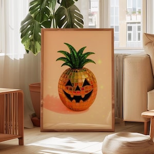 May include: A framed print featuring a Halloween-themed pineapple. The pineapple has a mosaic-like texture, a carved jack-o'-lantern face, and a green leafy top. The artwork is displayed in a well-lit room with wooden furniture.