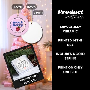 May include: A round, pink ceramic ornament with the text "mock berry" and a raspberry illustration. The back is white. The ornament is 3 inches in diameter and includes a gold string for hanging. The product is printed in the USA.
