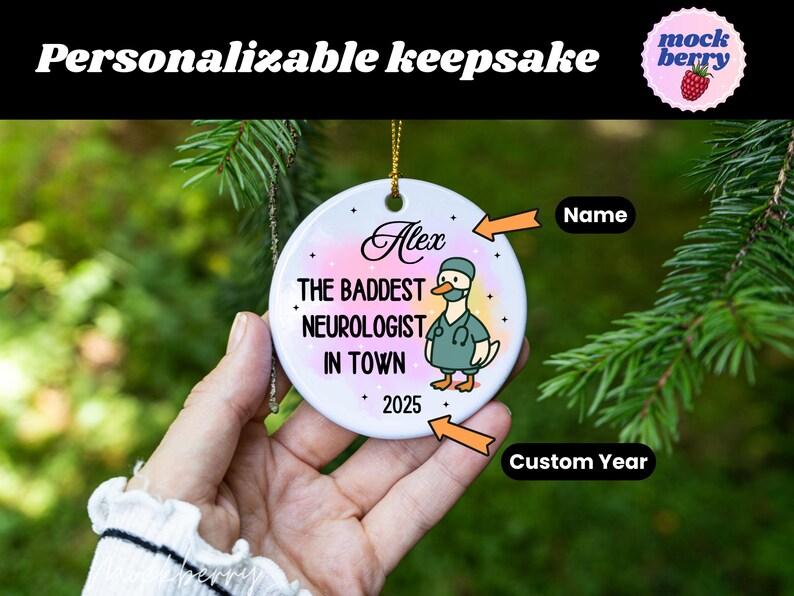 Puede incluir: Un adorno de recuerdo personalizable con el texto "Personalizable keepsake". El adorno presenta el nombre "Alex" y la frase "THE BADDEST NEUROLOGIST IN TOWN" con un pato de dibujos animados con uniforme. Tambi&eacute;n se muestra el a&ntilde;o "2025".