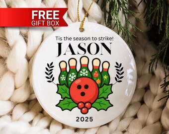 May include: White ceramic Christmas ornament with a bowling theme. The ornament features a red bowling ball, green bowling pins, and the text "Tis the season to strike!" and "JASON". The year "2025" is also displayed.