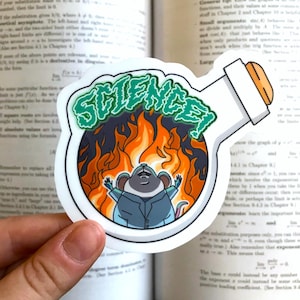 May include: A sticker featuring a cartoon mouse in a lab coat, arms raised in front of flames, inside a flask. The word "SCIENCE!" is written in green above the mouse. The flask has a white body and a brown stopper.
