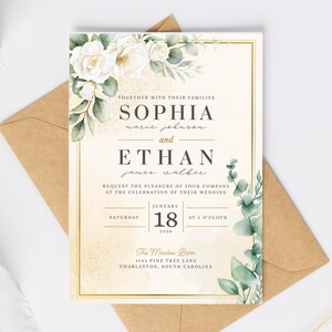 Puede incluir: Una tarjeta de invitación de boda rectangular con rosas blancas y hojas de eucalipto verdes en la parte superior y derecha. El texto dice Sophia Marie Johnson y Ethan James Walker, sábado 18 de enero de 2026 a las 2, The Meadow Barn, 4582 Pine Tree Lane, Charleston, South Carolina.