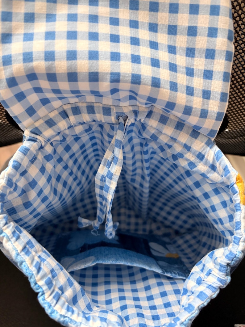 Peut inclure: Un sac &agrave; dos en tissu arborant un motif &agrave; carreaux vichy bleu clair et blanc. L'int&eacute;rieur comprend un syst&egrave;me de fermeture &agrave; cordon coulissant et une poche ouverte unique sur le panneau arri&egrave;re. Le rabat sup&eacute;rieur est doubl&eacute; du m&ecirc;me tissu vichy.