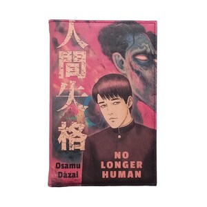May include: A pink and black book cover with a manga style illustration of a man with short black hair and a white shirt. The text on the cover reads "No Longer Human" and "Osamu Dazai".