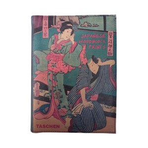 以下が含まれることがあります： 日本の木版画の2人の人物が伝統的な服装をしているヴィンテージスタイルの書籍カバー。カバーは緑色の背景に茶色で、「JAPANESE WOODBLOCK PRINTS」という文字がピンク色で書かれている。本のタイトルは「TASCHEN」です。