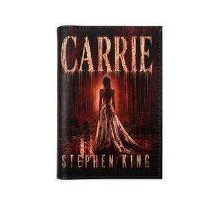 Könnte beinhalten: Ein rechteckiger schwarzer Bucheinband mit dem Titel CARRIE in verwitterter weißer Schrift oben und STEPHEN KING unten. Die Mitte zeigt eine Figur in einem langen, blutbefleckten weißen Kleid in einem dunklen, rot beleuchteten Raum.