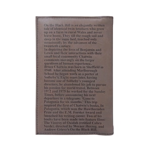 May include: A brown leather-bound book with the title "On the Black Hill" embossed on the front cover. The text describes the lives of twin brothers who grow up on a farm in rural Wales and never leave home. The book was inspired by the author's travels to Patagonia.