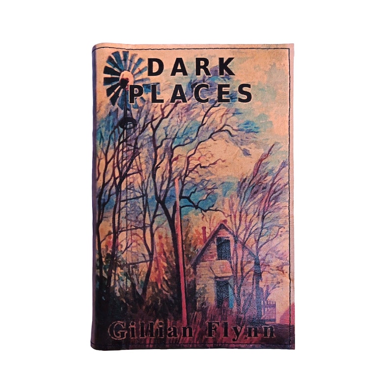 Puede incluir: Una portada de libro con el t&iacute;tulo "DARK PLACES" y el nombre de la autora, Gillian Flynn. La portada presenta una pintura a la acuarela de una escena rural con un molino de viento, una casa y &aacute;rboles desnudos.