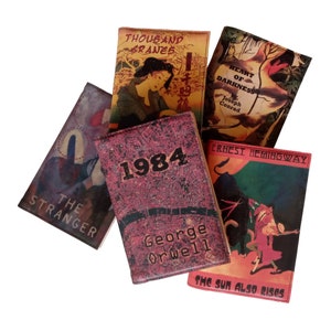 Puede incluir: Una colecci&oacute;n de portadas de libros con t&iacute;tulos de literatura cl&aacute;sica. Las portadas muestran dise&ntilde;os vintage con t&iacute;tulos como "1984" de George Orwell, "El Extranjero", "El coraz&oacute;n de las tinieblas", "The Sun Also Rises" y "Mil grullas". Las portadas tienen una est&eacute;tica antigua y desgastada.