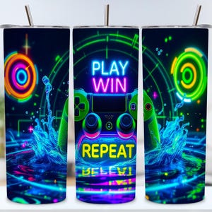 Może przedstawiać: Kubek ze stali nierdzewnej z żywym motywem gier. Kubek posiada neonowo-zieloną i niebieską grafikę kontrolera ze słowami "PLAY WIN REPEAT" w neonowych kolorach. Projekt zawiera rozpryski wody i geometryczne kształty.