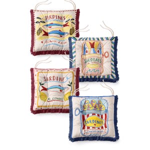 Pode incluir: Quatro almofadas quadradas para assento com laços, cada uma com ilustrações coloridas de sardinhas em lata com textos como Sardines, Al Limone e A l'huile d'olive. As almofadas têm franjas decorativas em vermelho escuro ou azul.