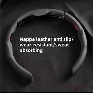 May include: A black Nappa leather steering wheel cover with a perforated design. The text on the cover reads "Nappa leather anti slip/ wear-resistant/ sweat absorbing". The cover is designed to improve grip and absorb sweat.