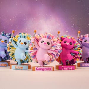 May include: Five colorful hedgehog figurines with pom-pom manes and personalized nameplates. Each holds a baton with orange tips. The figurines are in shades of blue, pink, and purple, with the word "Congrats" on one base.