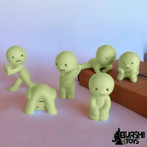 May include: Five light green figurines in different poses. One is upside down, another is kneeling, and others are standing or reclining. The figurines have simple, rounded features and a minimalist design. The Burshi Toys logo is in the bottom right corner.