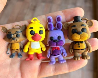 May include: Four colorful figurines of characters from a popular video game franchise. The figures include a brown fox with an eye patch, a yellow chick, a purple rabbit, and a brown bear with a black hat. Each figure has unique features.