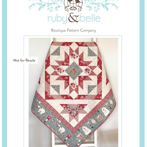 May include: A handmade quilt with a star pattern in red, cream, and teal. The quilt features a central star design with floral accents and a border with whimsical illustrations. The text "Isabelle Star Quilt" is at the bottom.