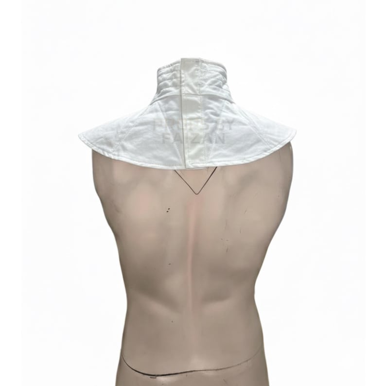 May include: White padded fencing collar with a high, structured neck and a wide, rounded collar. The collar is designed to protect the neck and shoulders during fencing. The fabric appears to be a sturdy, quilted material.