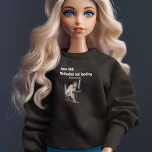 May include: A doll with long blonde hair and blue eyes wearing a black sweatshirt and blue trousers. The sweatshirt has the text "Error 404: Motivation not loading" and a graphic of a person at a computer.