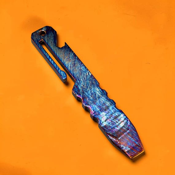 Titanium prybar with flame anodizing that leaves swirling rainbow colors — the heat-treatment finish makes each one a one-of-a-kind piece of functional art.