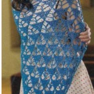 May include: A blue crocheted shawl with a leaf-like pattern. The shawl is draped over the shoulders, showcasing the intricate openwork design. The color is a vibrant blue, and the shawl appears to be made of a soft yarn.