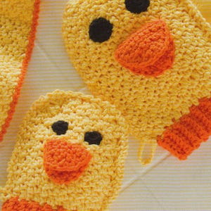 May include: Close-up of two yellow crochet duck-shaped items with orange beaks and feet, and black eyes. The items are handmade and appear to be part of a larger set, possibly a baby toy or bath mitts.