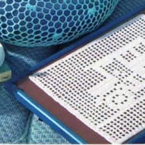 Puede incluir: Una taza y un platillo blancos con líquido azul, descansando sobre una pila de libros. Un mantel individual de ganchillo con texto está en un marco azul. Un cuenco decorativo azul está en el fondo. La escena está sobre una superficie azul.