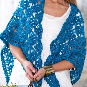 May include: A bright blue crochet shawl featuring a textured, open-work pattern with raised bobble stitches throughout. The shawl is draped over the shoulders, showcasing a repeating geometric design and a scalloped edge along the bottom border.