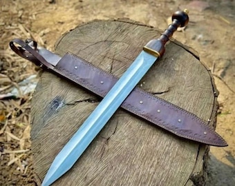 May include: A Roman gladius sword with a polished steel blade and a wooden handle with a dark pommel. The sword rests on a wooden tree stump, with a brown leather sheath. The sheath is decorated with rivets and stitching.