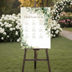 May include: A wedding seating chart on a wooden easel. The sign features the text "Find Your Seat" and guest names, with a botanical design of green leaves and gold accents. The background is a soft, watercolor-style wash.