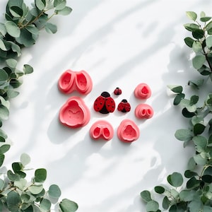May include: A collection of pink, butterfly-shaped molds and ladybug-shaped decorations. The ladybugs are red with black spots and black bodies. The molds are in various shapes and sizes, perfect for crafting or baking.