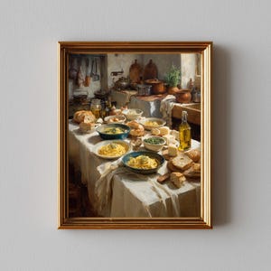 May include: A framed print of a kitchen scene with a table laden with food. Bowls of pasta, bread, cheese, and olive oil bottles are arranged on a white tablecloth. The background shows cooking utensils and pots, creating a warm, inviting atmosphere.