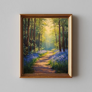 May include: A framed painting depicting a woodland scene. A path winds through the forest, bordered by bluebells. Sunlight filters through the trees, illuminating the path. The frame is gold-coloured.