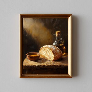 Puede incluir: Pintura enmarcada de naturaleza muerta. Un pan, un cuenco pequeño con líquido y una botella de vidrio con aceite y tapón de corcho están dispuestos sobre una superficie de madera. La pintura tiene una paleta de colores cálidos.