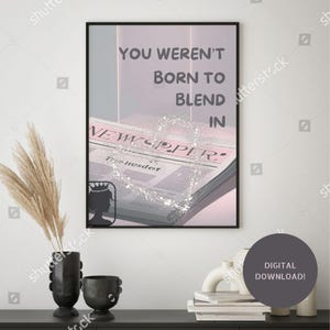 May include: A framed print with the text "YOU WEREN'T BORN TO BLEND IN" over a newspaper illustration. The print has a black frame and is displayed on a white wall. A digital download is available.