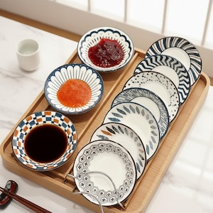 May include: A wooden serving tray displays a selection of small ceramic plates and bowls. The plates have diverse patterns in blue, white, and brown, some containing food. Chopsticks and a small white cup are also visible.