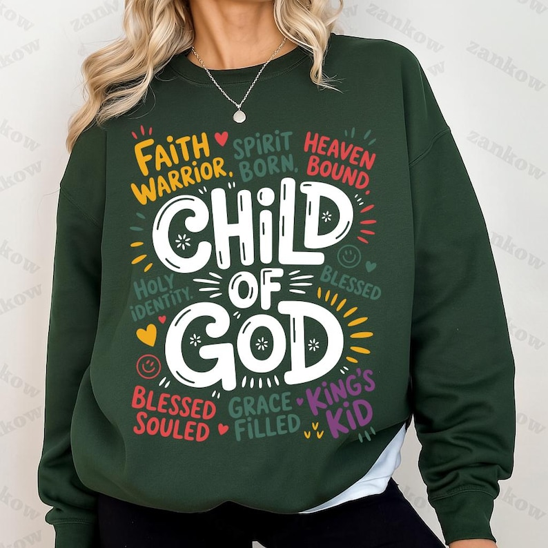 A woman in a forest green sweatshirt with the “Child of God” design in the center, surrounded by uplifting Christian phrases in multiple bright colors.