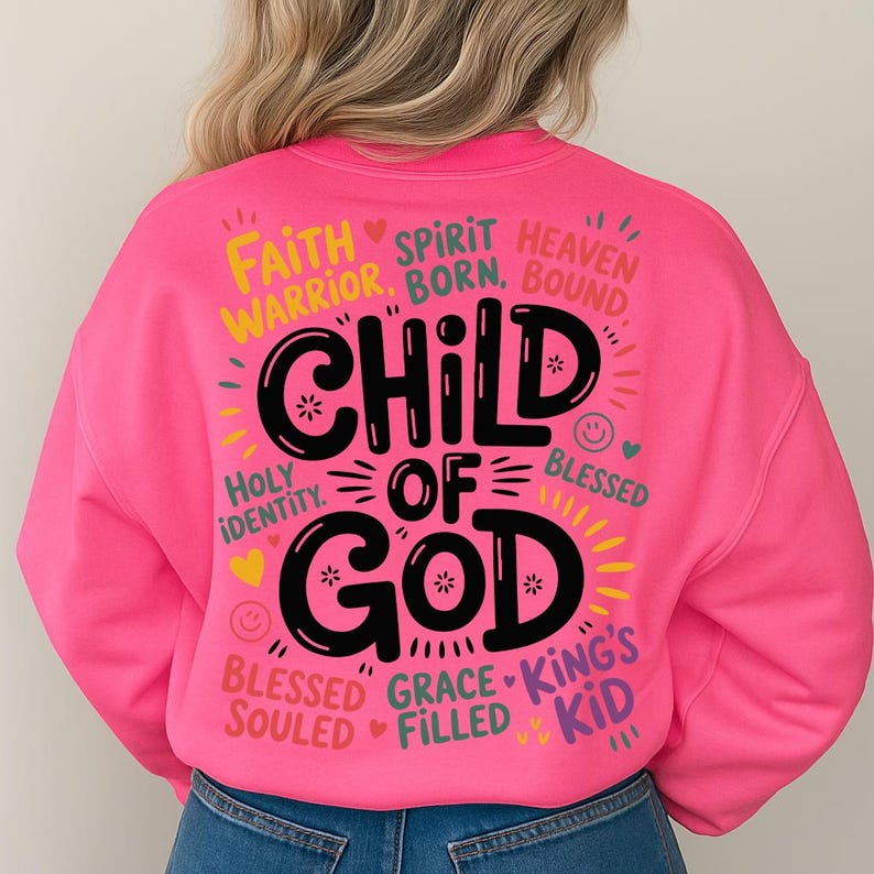 Back view of a woman in a bright pink sweatshirt showcasing the bold “Child of God” design filled with spiritual affirmations and cheerful decorative elements.