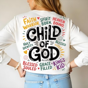 Back view of a woman in a white sweatshirt featuring the bold “Child of God” text surrounded by faith-inspired phrases in a colorful layout.