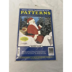 Könnte beinhalten: Eine Packung mit Holzarbeitsmustern mit einem sitzenden Weihnachtsmann in einem Schlitten. Die Packung enthält Anweisungen für eine 3D-Anzeige, mit dem Text "FULL SIZE WOODCRAFT PATTERNS" oben.