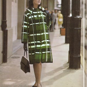 May include: A vintage green and white plaid coat with a matching collar and large buttons. The coat is worn with black gloves, a black purse, and black bow-tie shoes. The woman is standing on a sidewalk.