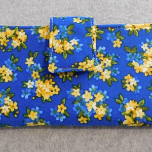 May include: A blue fabric wallet with a floral pattern in yellow and white. The wallet has a flap closure.