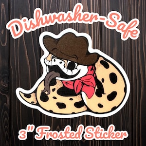 May include: A 3-inch frosted sticker featuring a cartoon snake wearing a cowboy hat and a red bandana. The snake has a tan body with black spots and a long tongue. The text "Dishwasher-Safe" and "Frosted Sticker" are in a cursive font.