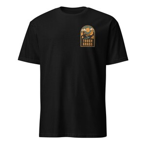 May include: Black t-shirt with a small, rectangular patch featuring a landscape design. The patch includes mountains, a river, and a sun, with the text "TOUCH GRASS" in a bold font. The shirt is made of a soft material.